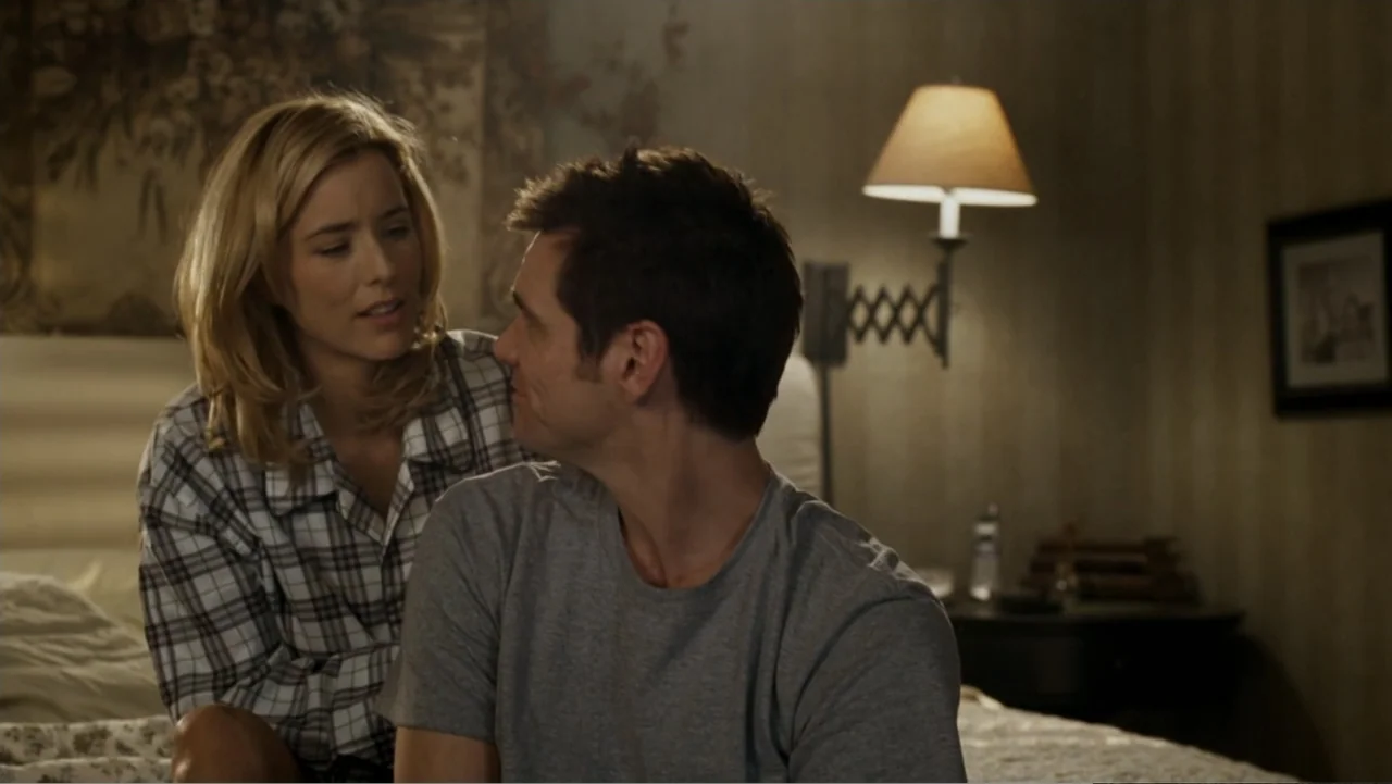 Fun with Dick and Jane (2005) movie still: medium — A bedroom contains a bed with textured bedding and a wall lamp mounted above. A man and a woman…