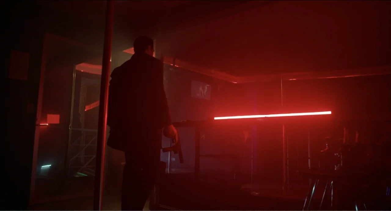Instantes Capturados (2022) movie still: fullbody — A dark, smoke-filled nightclub interior is lit by a single prominent red neon light. A man in a…