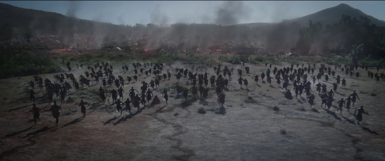 The Woman King (2022) movie still: wide — A vast, open plain with patches of dry vegetation and rising smoke columns. A dense crowd of people in…