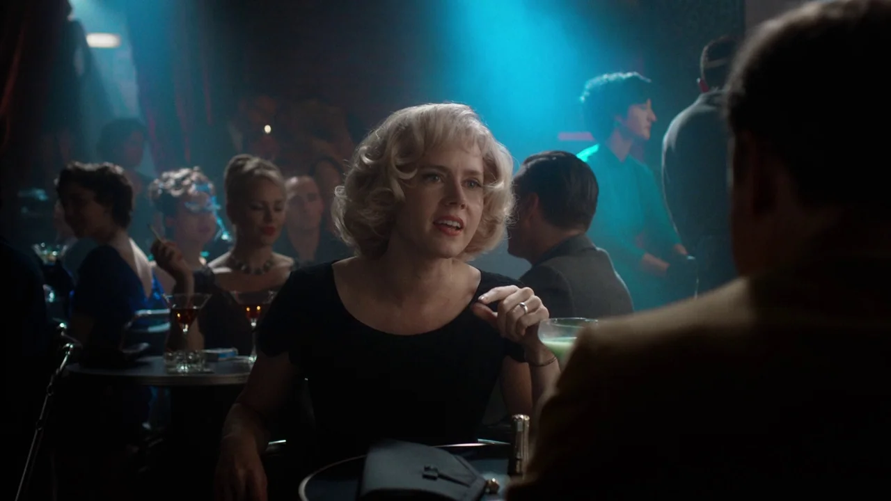 Big Eyes (2014) movie still: medium — A dimly lit 1950s nightclub with patrons seated at small round tables. A blonde woman talks to an unseen man…