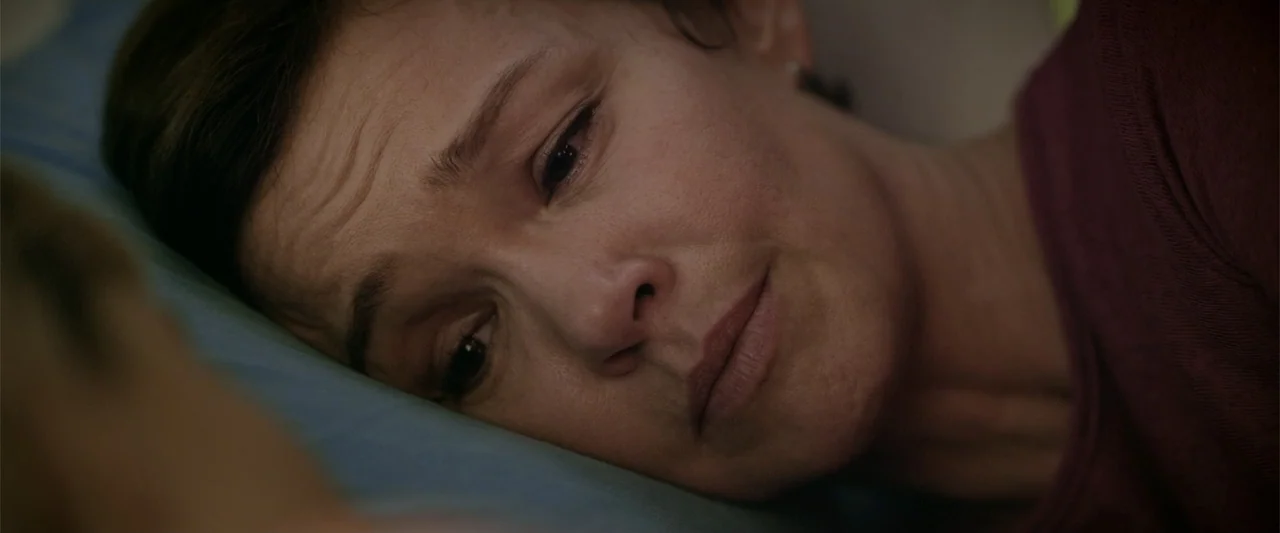 Dirty Little Secret (1998) movie still: closeup — A close-up of a woman resting her head on a blue pillow. The subject lies sideways on the bedding…