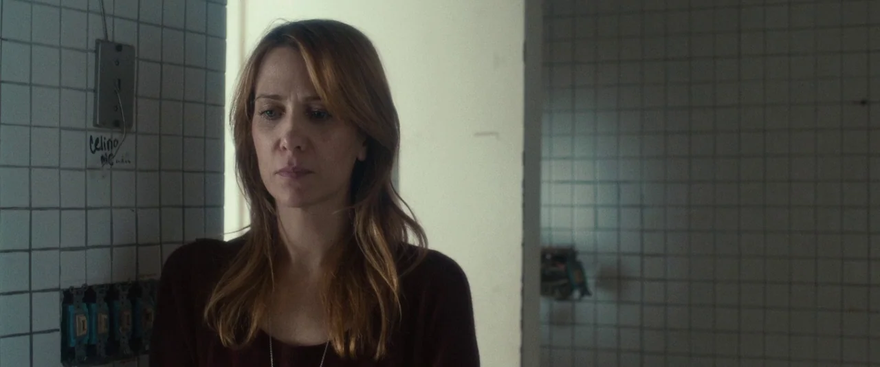 The Skeleton Twins (2014) movie still: medium — A woman stands in a doorway against walls covered in white rectangular tiles. Exposed electrical…