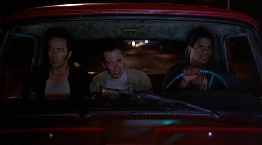 Mystery Train (1989) movie still: medium — Three men occupy the front bench seat of a dark sedan during a night drive. The camera is mounted on the…