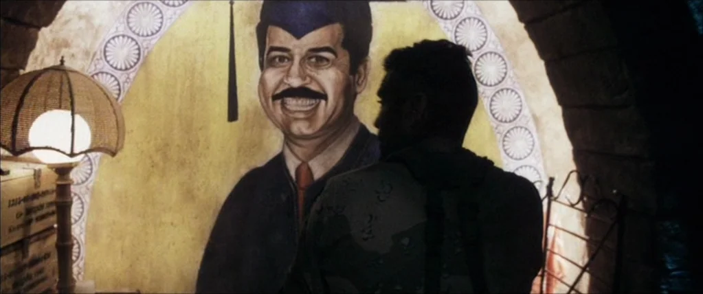 Three Kings (1999) movie still: medium — A subterranean structure with arched stone walls features a painted mural of a smiling man. A soldier in…