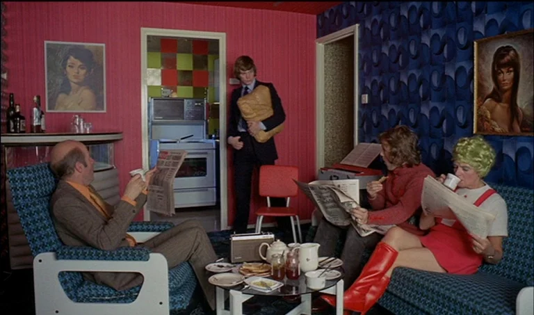 A Clockwork Orange (1971) movie still: wide — A 1960s living room features striking magenta walls and deep blue patterned wallpaper. Four…