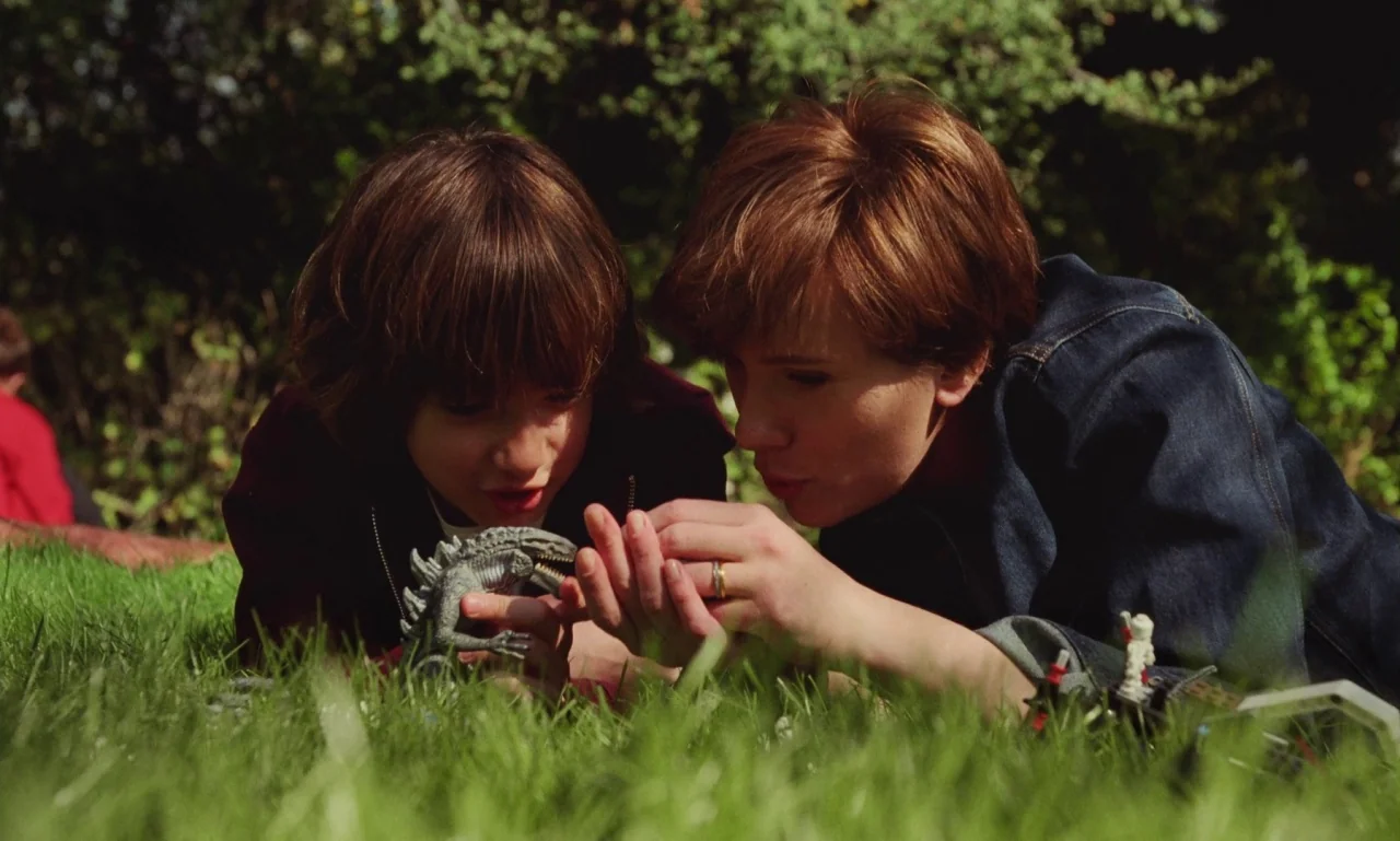 Marriage Story movie still: medium — A sunny patch of green grass provides the surface for two people lying down. A woman and a young child interact…