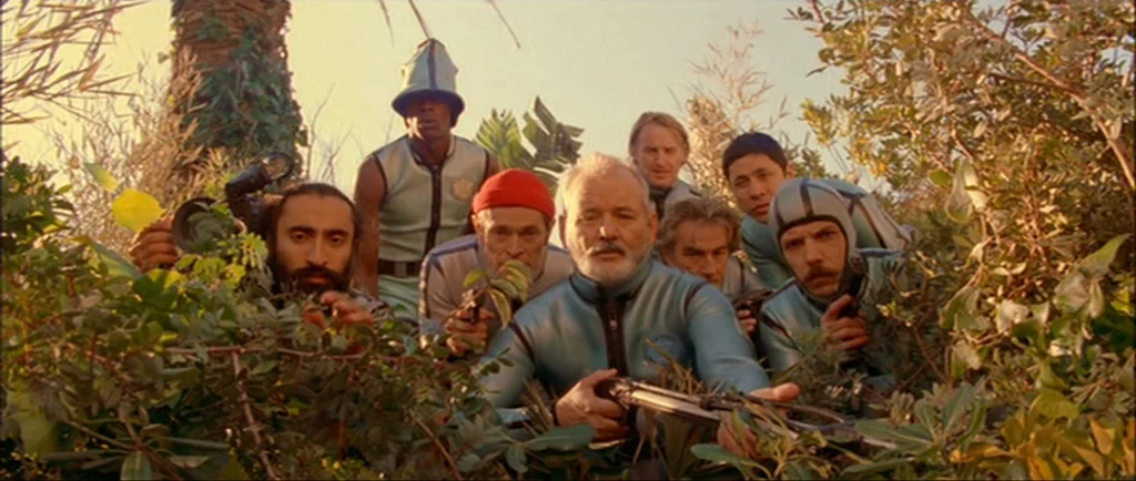 The Life Aquatic With Steve Zissou (2004) movie still: medium — A group of men in matching blue diving gear crouch within thick, dense foliage. They…