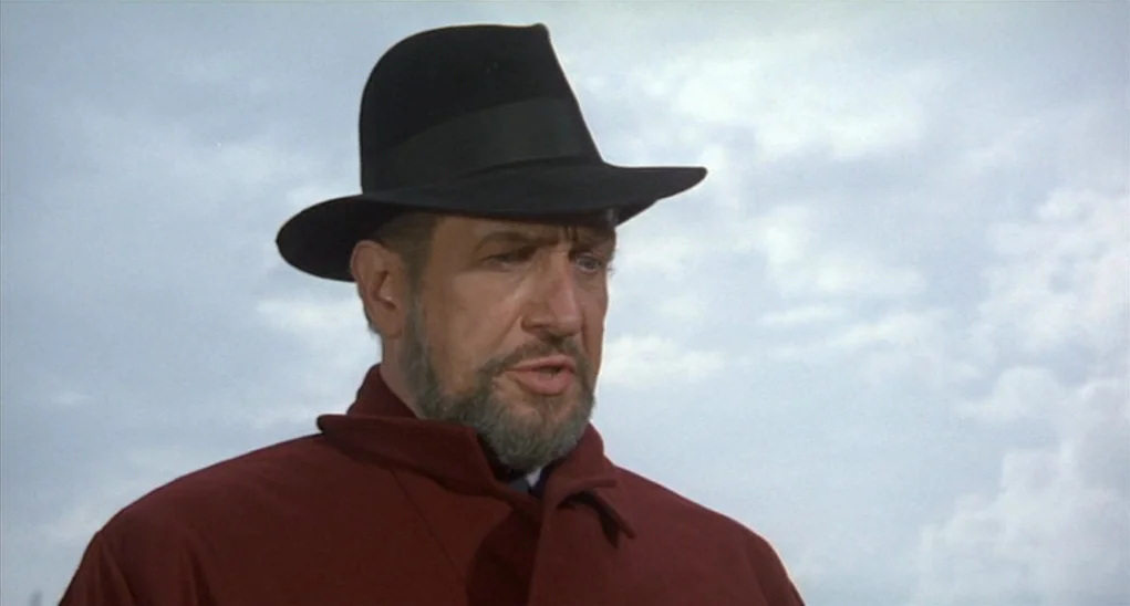 Dr. Goldfoot and the Girl Bombs (1966) movie still: medium — A man stands outdoors under a bright, overcast sky with light clouds visible. The…