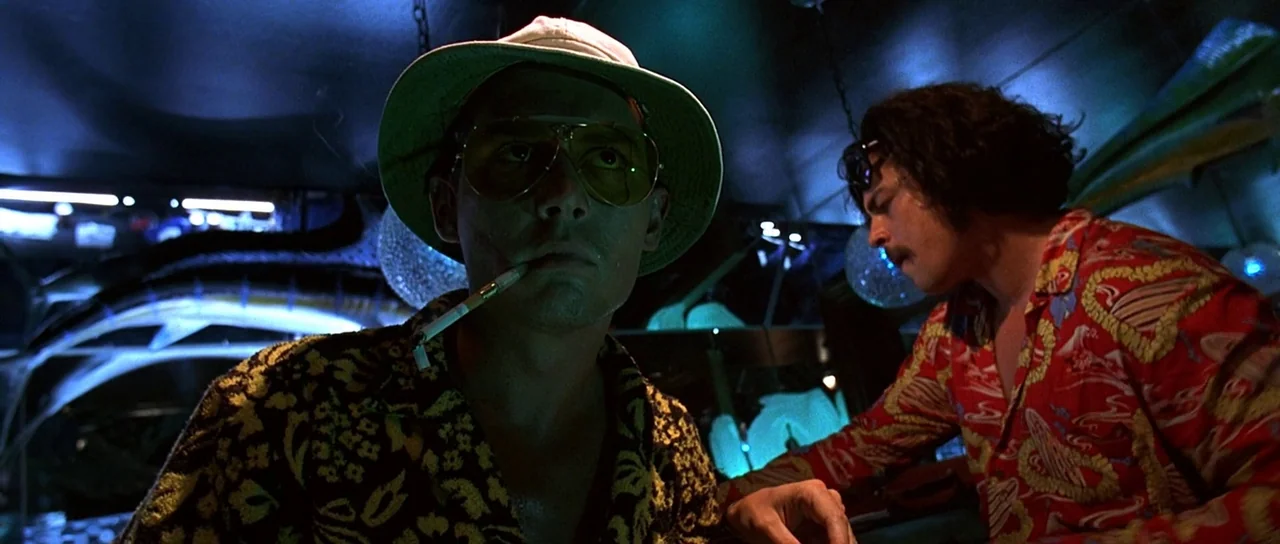 Fear and Loathing In Las Vegas (1998) movie still: medium — A dimly lit interior space with dark surfaces and saturated colorful neon light sources.…