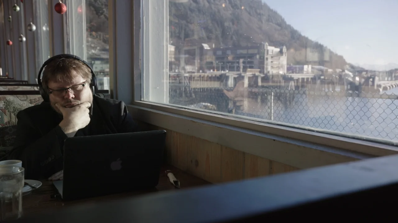 Kill Chain: The Cyber War on America's Elections (2020) movie still: medium — A man sits at a table inside a diner booth looking at his laptop.…