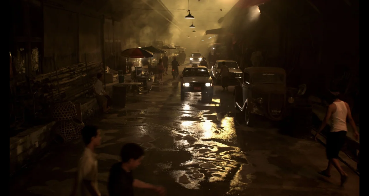 Ninja: Shadow of a Tear (2013) movie still: wide — A dark, narrow city alley is illuminated by sparse overhead lamps and hazy smoke. A taxi travels…
