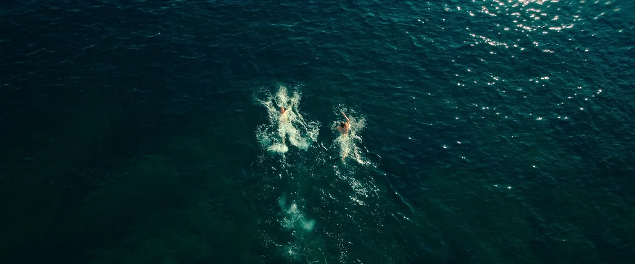 The Count of Monte-Cristo (2024) movie still: wide — A vast expanse of deep blue ocean water spans the frame with high contrast ripples. Two…