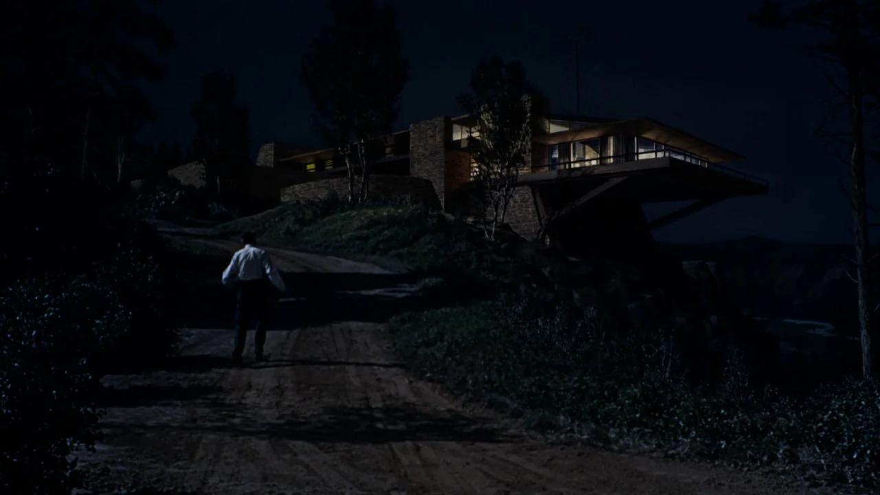 North By Northwest (1959) movie still: wide — A modernist residence with cantilevered architecture sits atop a dark, rocky hill at night. A lone man…