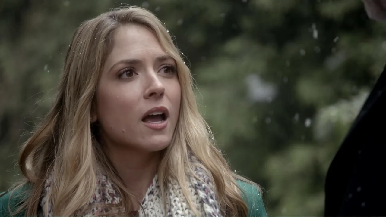 The Christmas Cure (2017) movie still: closeup — The setting is an outdoor area during a light snowfall with blurred greenery visible. A young…