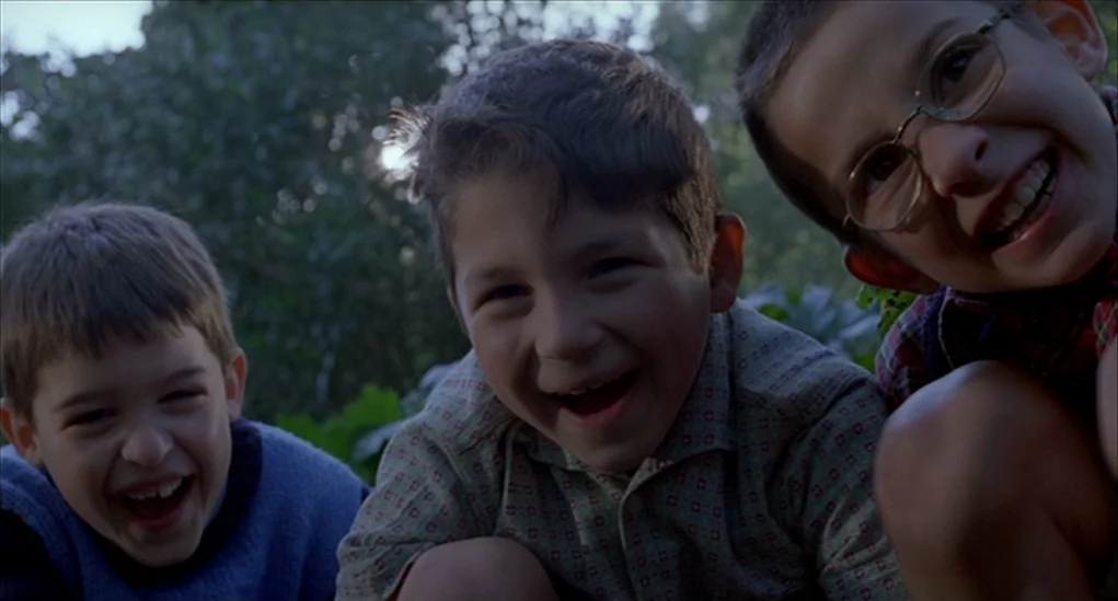 Anatomy of Hell (2004) movie still: medium — Three young boys are positioned close to the camera in an outdoor setting. The children are laughing…
