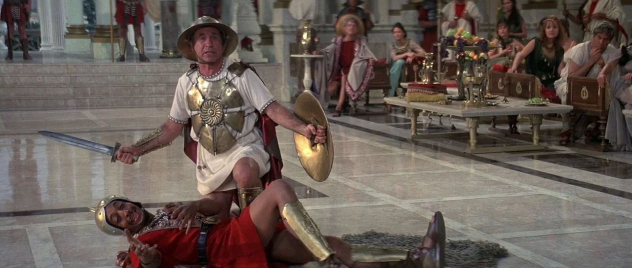 History of the World: Part 1 (1981) movie still: fullbody — A spacious marble floor banquet hall features decorated white columns and distant seated…
