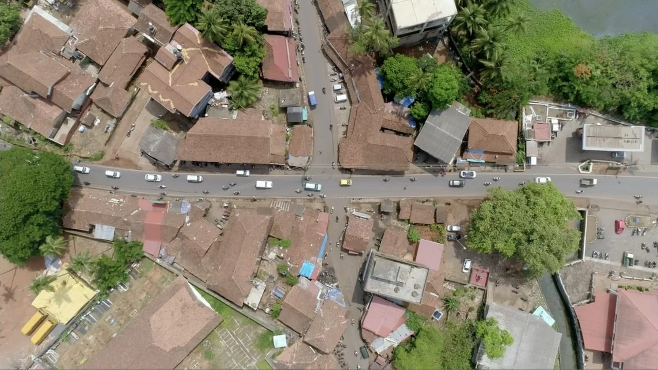 Finding the Way Home (1991) movie still: establishing — An aerial view captures a T-junction intersection surrounded by densely packed low-rise…