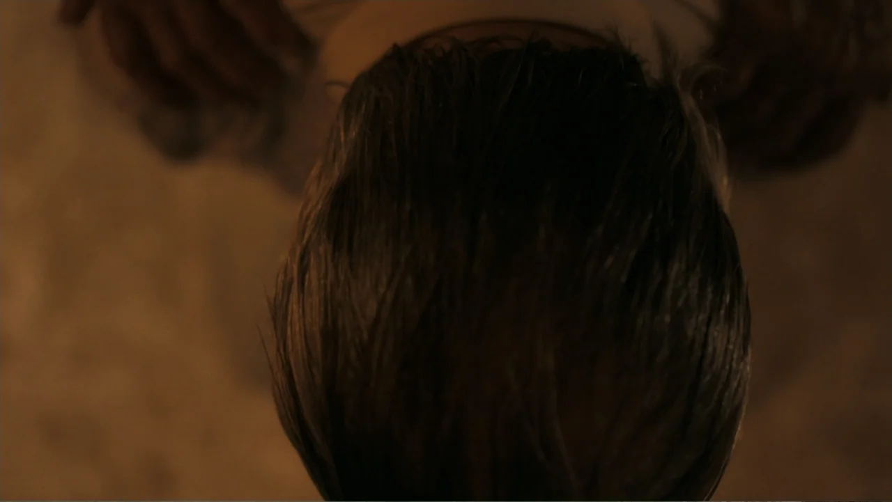 Alabama Snake (2020) movie still: closeup — A dimly lit indoor space features warm golden-toned lighting focused on a dark surface. The top of a…