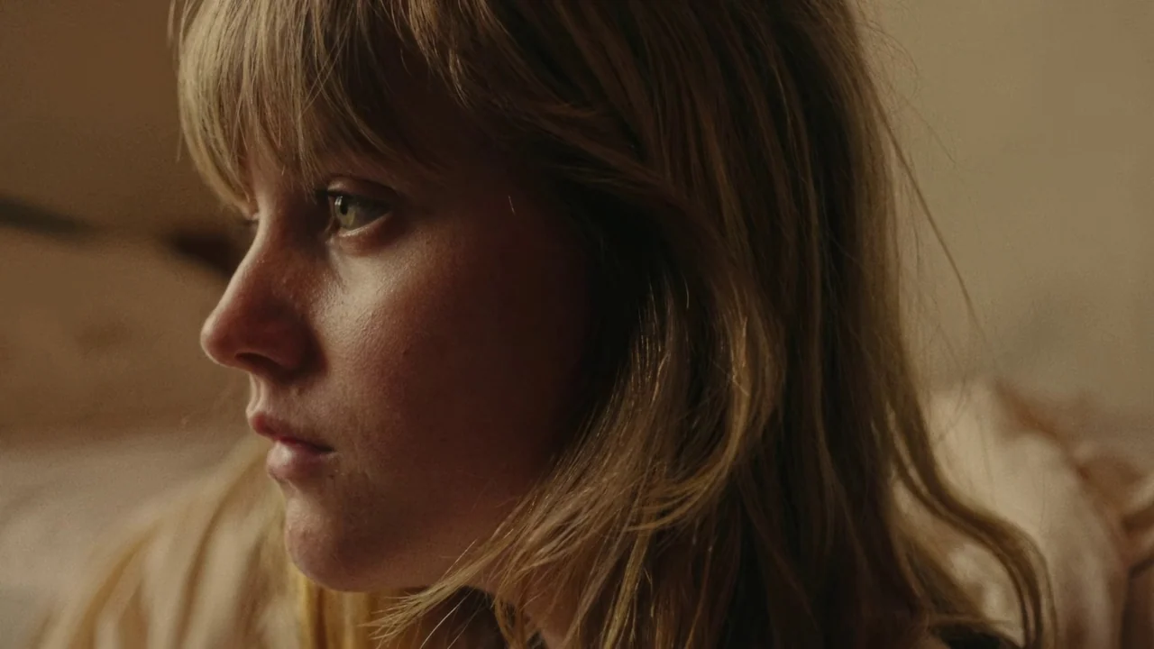 My First Summer (2020) movie still: closeup — A close-up view of a young woman inside a softly lit domestic space. The woman looks away from the…