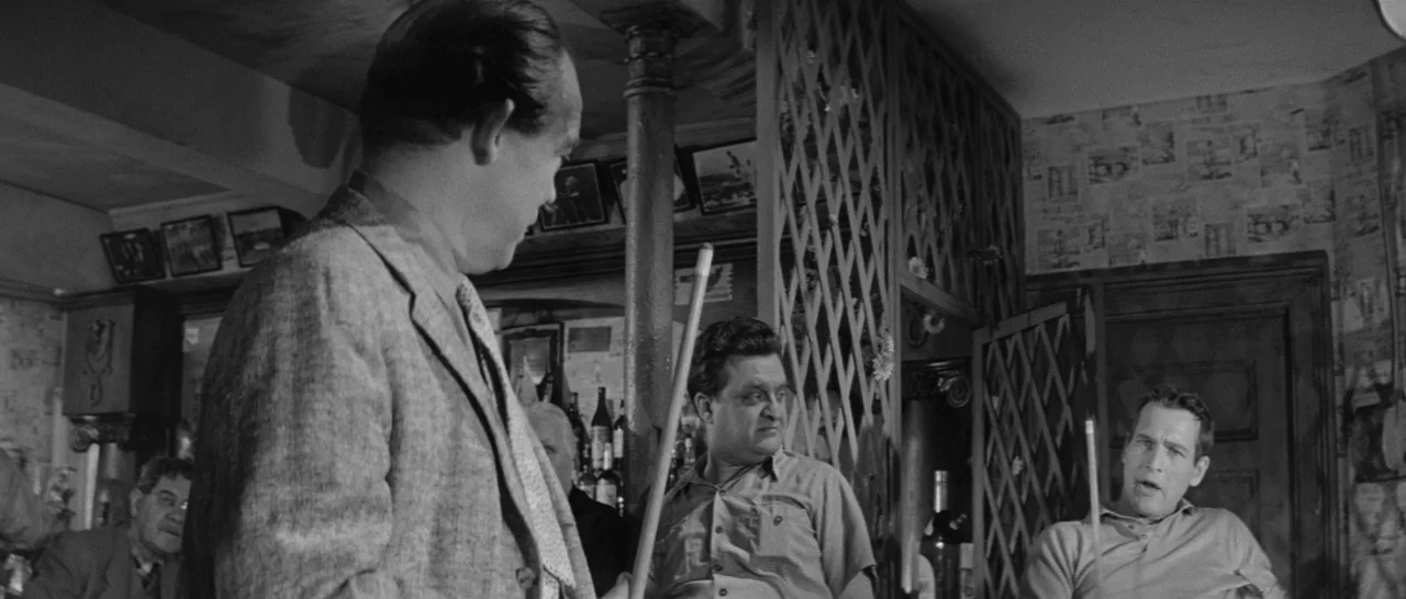 The Hustler (1961) movie still: medium — An interior pool hall space with patterned wallpaper and a wooden lattice partition. Two men stand in the…