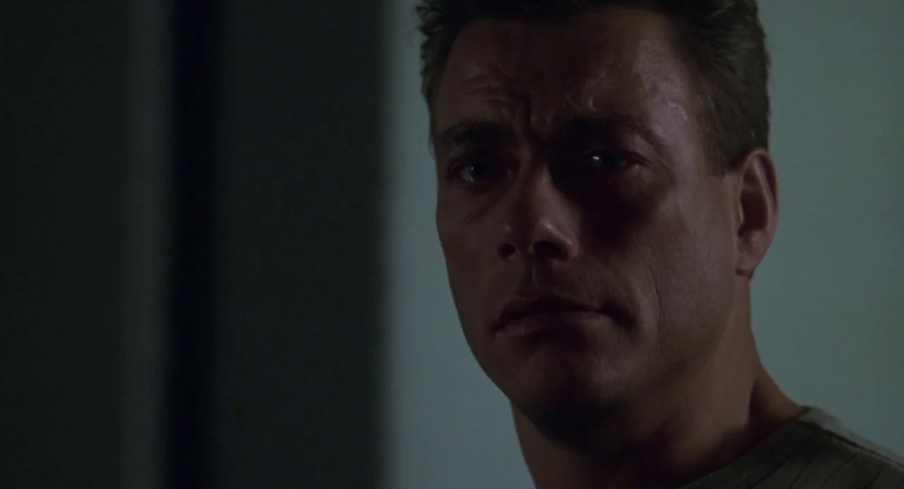Universal Soldier: The Return (1999) movie still: closeup — A dimly lit room provides a dark background for the close-up shot. The subject faces the…