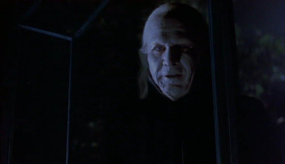Bram Stoker’s Dracula (1992) movie still: closeup — An elderly man is framed within the dark structure of a phone booth at night. Pale light…
