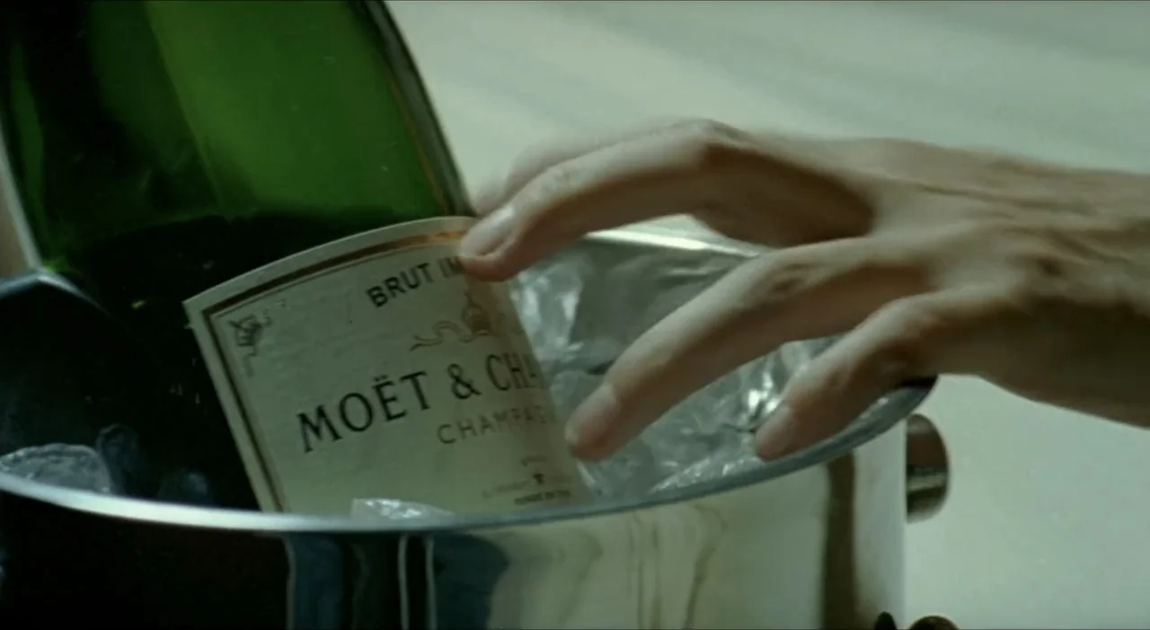 Sex, Love And Other Perversions II (2006) movie still: closeup — A close-up view shows a metal ice bucket holding a bottle of champagne. A hand…