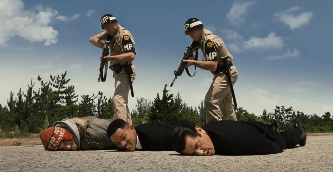 Men in Black 3 (2012) movie still: fullbody — An open asphalt road under a bright blue sky with scattered light clouds. Two armed MPs stand behind…