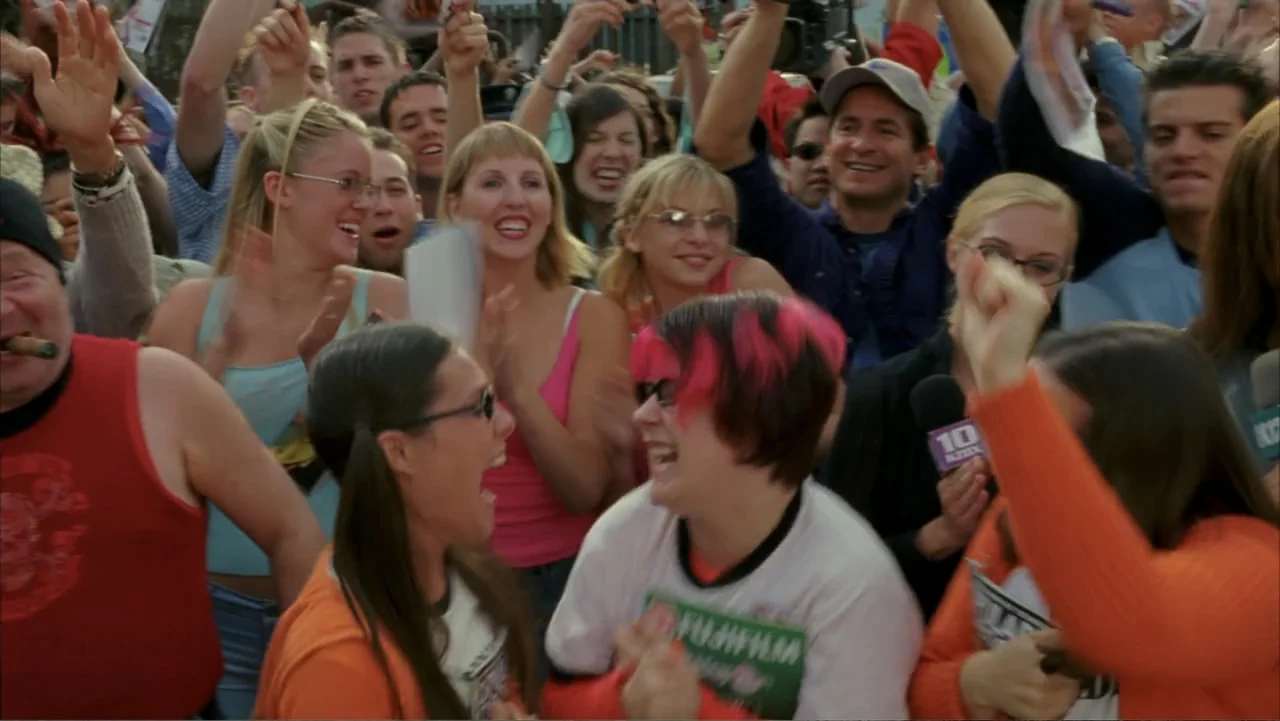 Scooby-Doo 2: Monsters Unleashed (2004) movie still: medium — A diverse crowd of young people stands outdoors at a public event. They are cheering,…