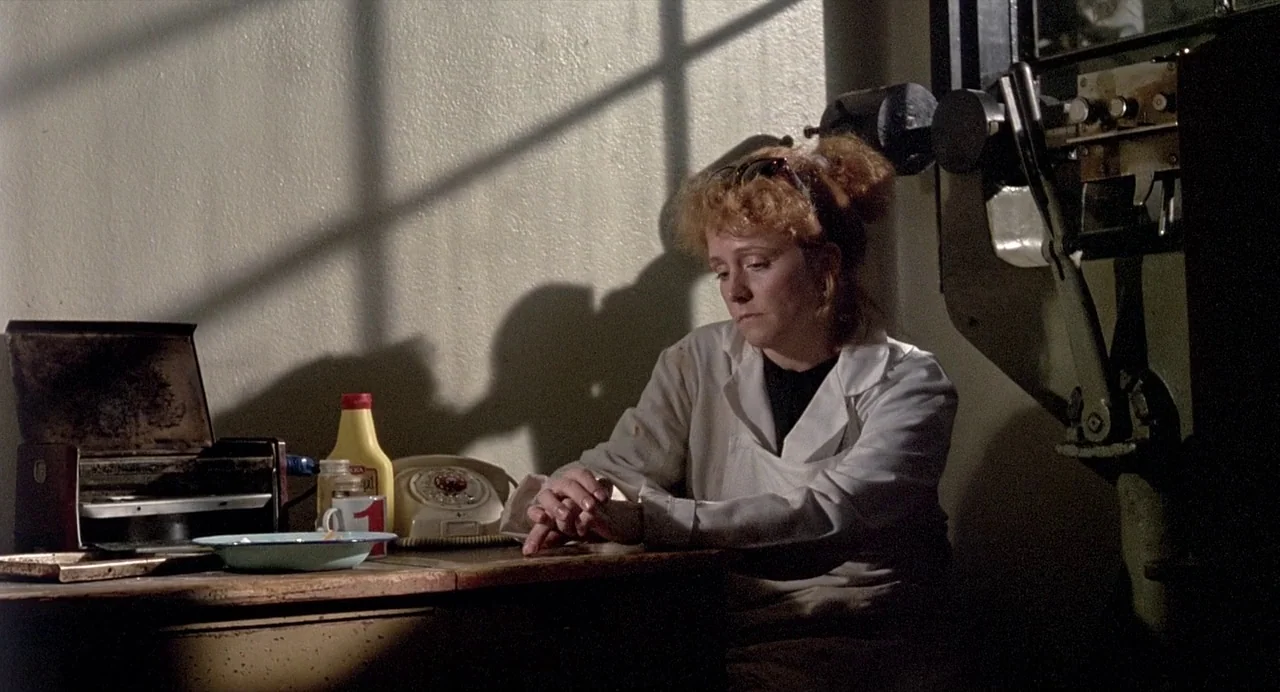 Ariel (1988) movie still: medium — A worn workroom features a desk cluttered with a mustard bottle, telephone, and tray. A woman in a white coat…