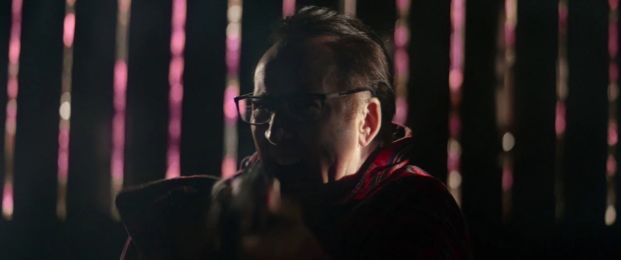 Colour Out of Space (2020) movie still: medium — A dark space features vertical pink neon light tubes in the distant background. A middle-aged man…