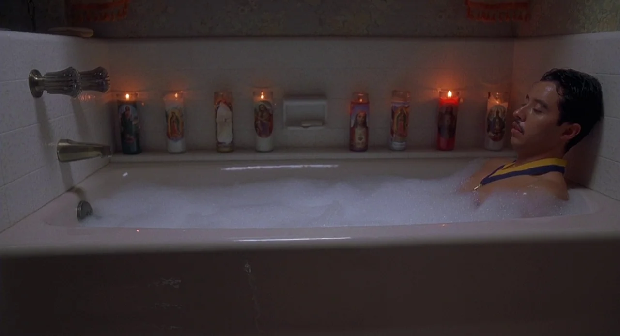 Napoleon Dynamite (2004) movie still: medium — A tiled bathroom features a pink bathtub lined with various lit religious votive candles. A man rests…