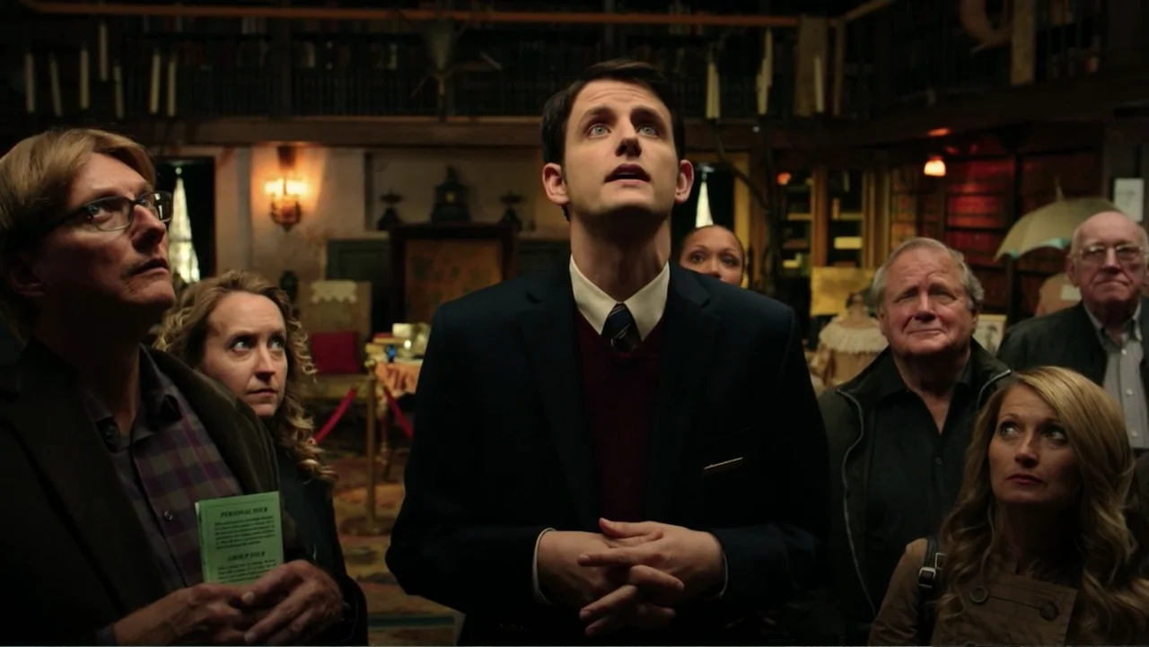 Ghostbusters (2016) movie still: medium — A dimly lit room with bookshelves lining the walls and a museum tour group. The group of six people stands…