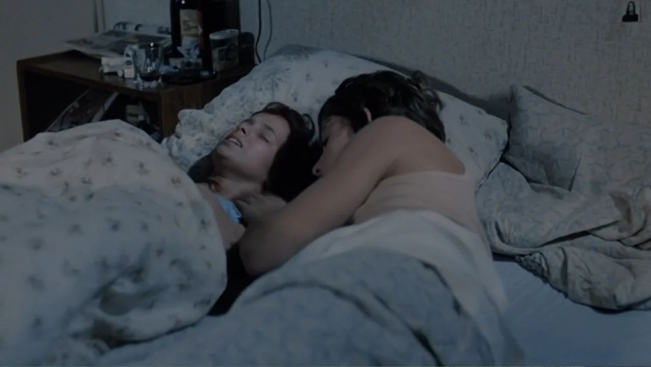 Christiane F. (1981) movie still: medium — Two people rest in a dimly lit room under patterned bedding. They lie close together in a bed while…