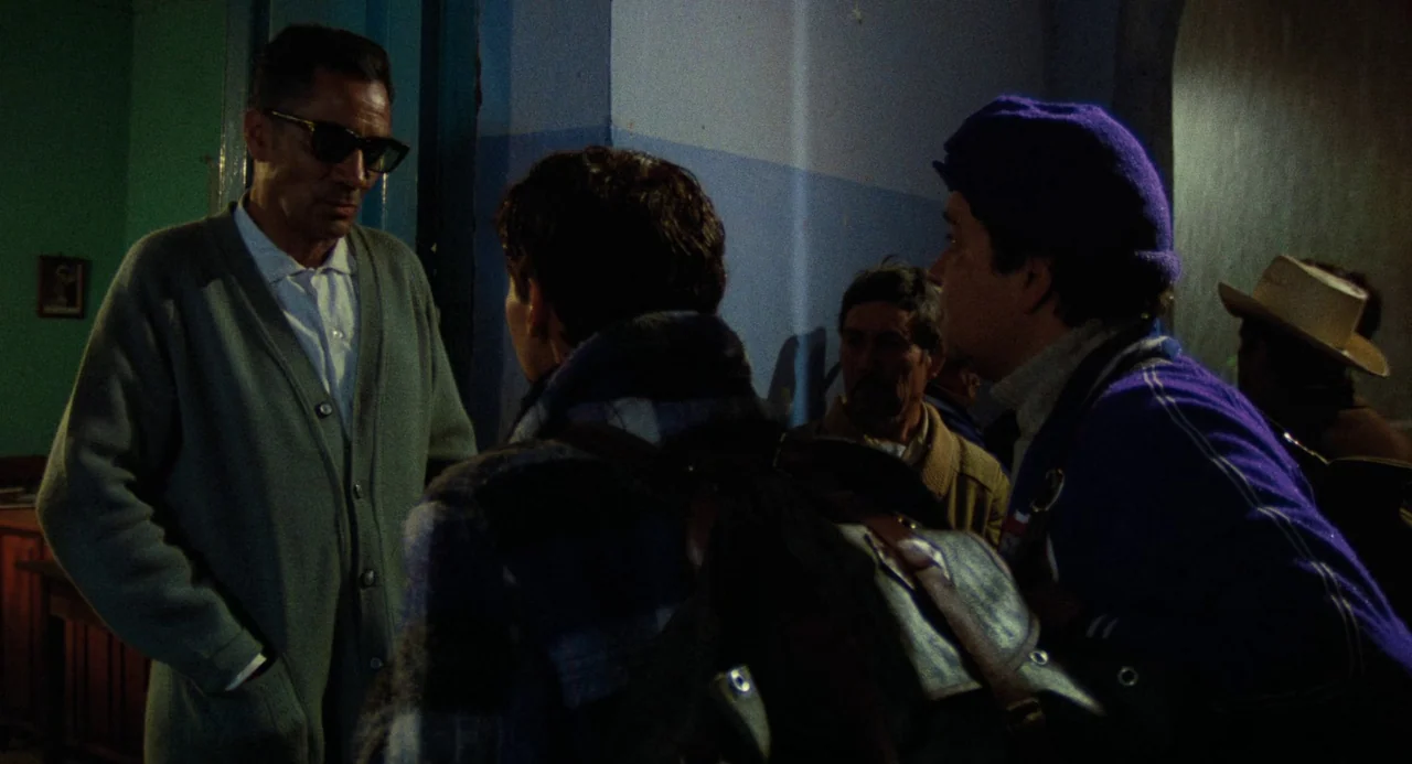 Canoa: A Shameful Memory (1976) movie still: medium — A dimly lit indoor passage features blue-painted walls and several individuals gathered…