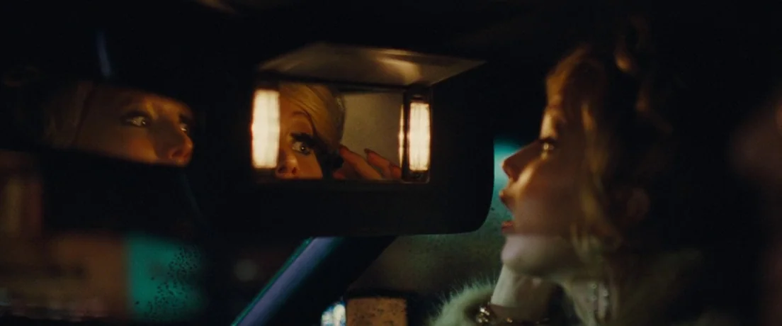 American Hustle (2013) movie still: medium — The interior of a vehicle at night with a vanity mirror flipped down. A woman looks at her reflection…