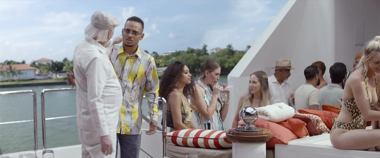 Father of the Bride (1991) movie still: medium — A group of people congregate on the deck of a large private yacht. Two men stand in the foreground…