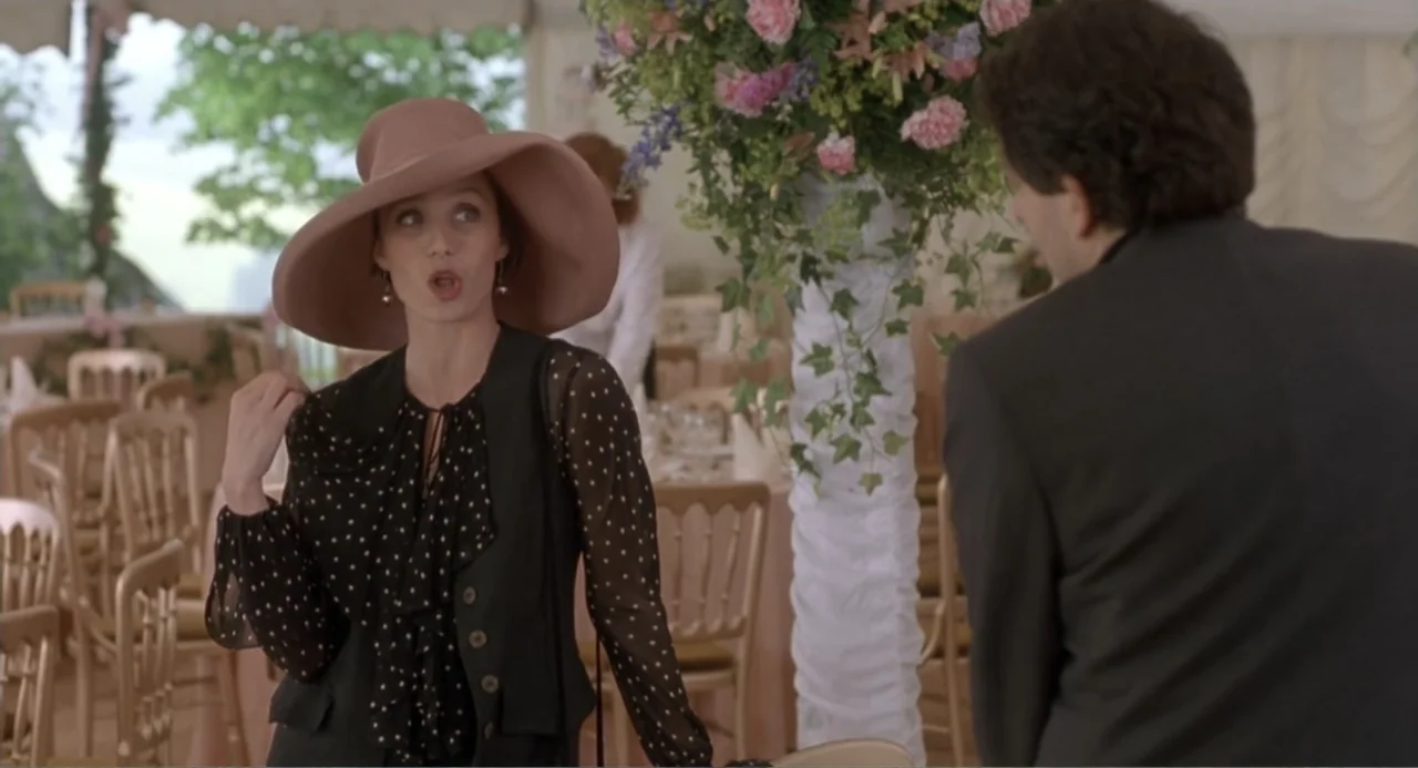 Four Weddings and a Funeral (1994) movie still: medium — A decorated white event tent contains floral arrangements and wooden chairs for guests. A…