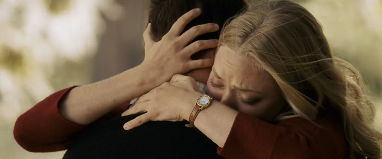 Dear John (2010) movie still: closeup — A sunlit park area during late afternoon with blurred trees in the background. A blonde woman hugs a man…