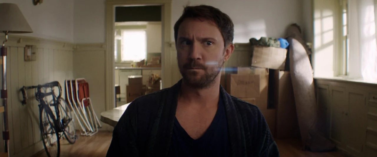 Seven Stages to Achieve Eternal Bliss (2018) movie still: medium — A living room cluttered with packed cardboard boxes and a bicycle leaning against…