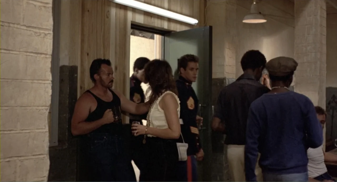 American Ninja 2: The Confrontation (1987) movie still: medium — An interior space with wooden slat walls and white painted brick pillars. A man and…