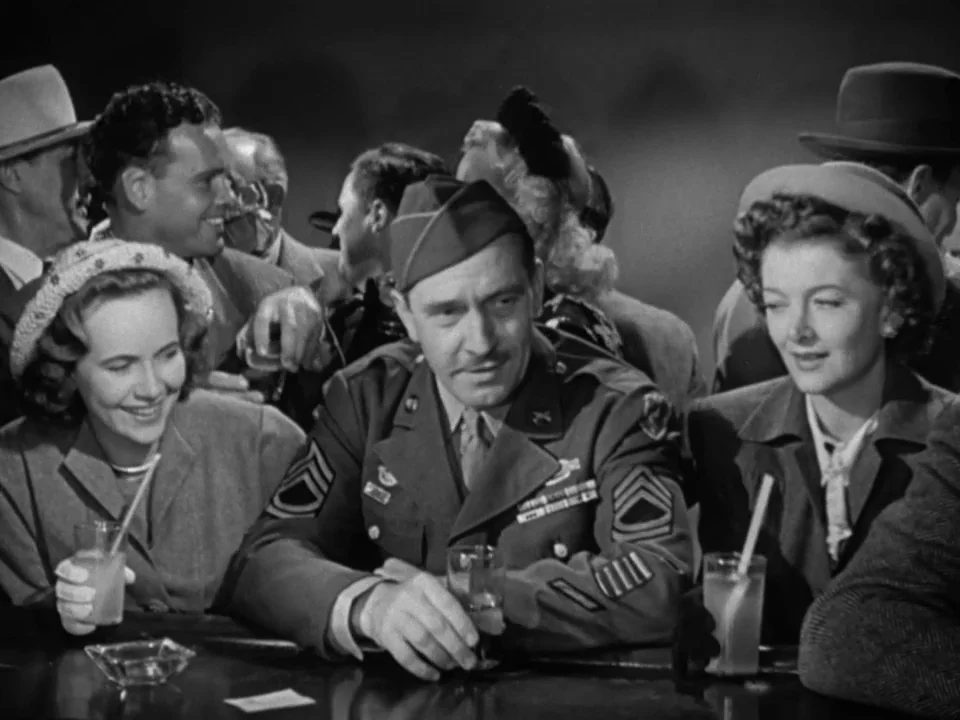 The Best Years of Our Lives (1946) movie still: medium — A crowded bar setting features a man in uniform flanked by two women. They sit at a dark…
