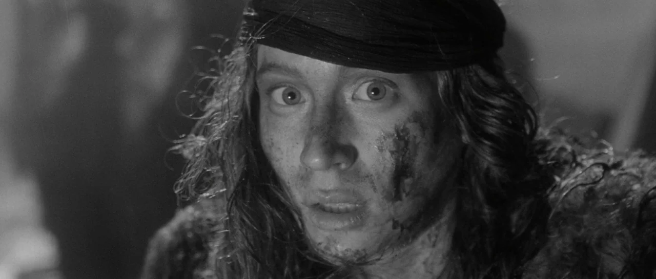 She Is Conann (2023) movie still: closeup — A dimly lit, indistinct dark space provides a backdrop for a dirt-smeared face. A person with dark hair…