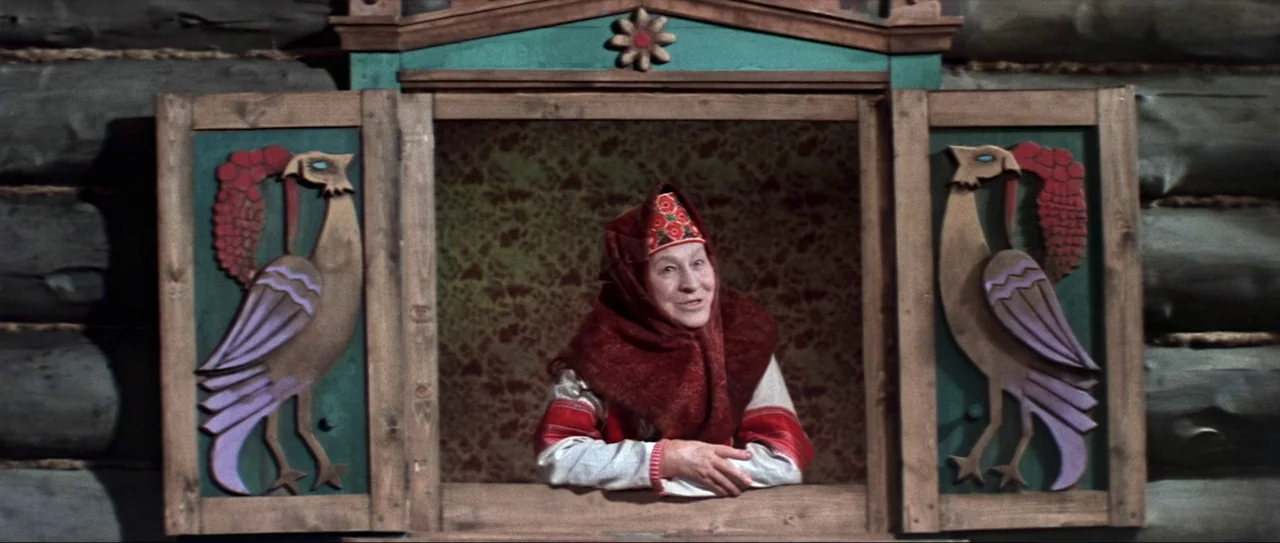 Through Fire, Water and… Brass Pipes (1968) movie still: medium — A woman leans out of a window with hand-painted wooden shutters displaying bird…