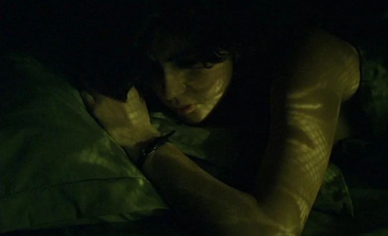 The Double Life of Véronique (1991) movie still: closeup — A person lies on a pillow in a dark bedroom at night. Patterns of light from external…