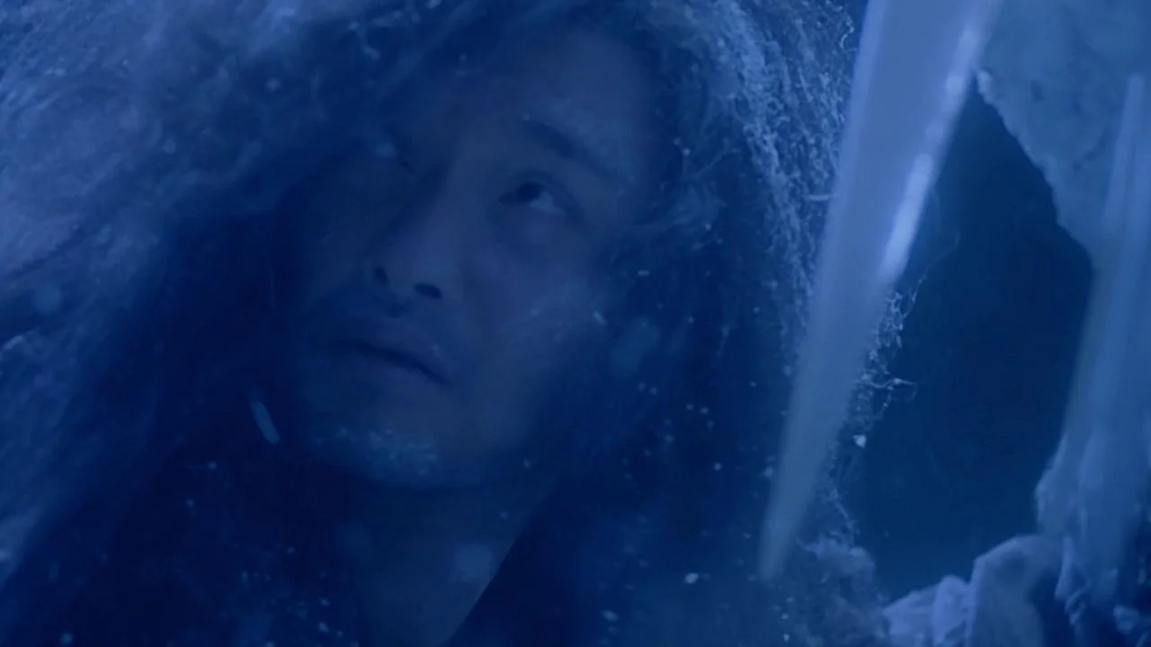 The Bride with White Hair II (1993) movie still: closeup — A man's face is partially obscured by hanging ice and frost in a cave. He looks upward…