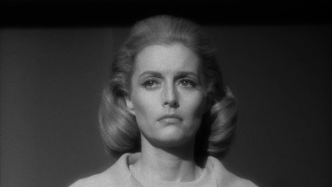 The Naked Kiss (1964) movie still: closeup — A woman is centered against a flat, dark, undifferentiated background. She stares forward while light…