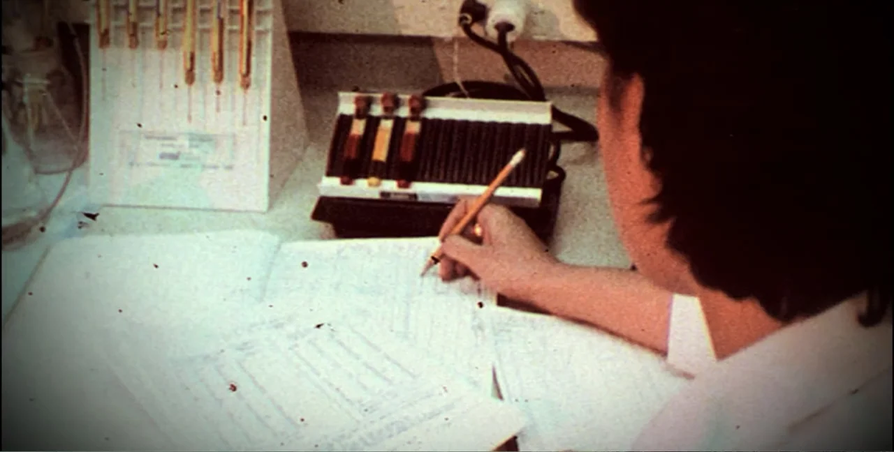 Alien Abduction: Travis Walton (2022) movie still: medium — A laboratory workspace features scientific testing equipment and various paper documents…