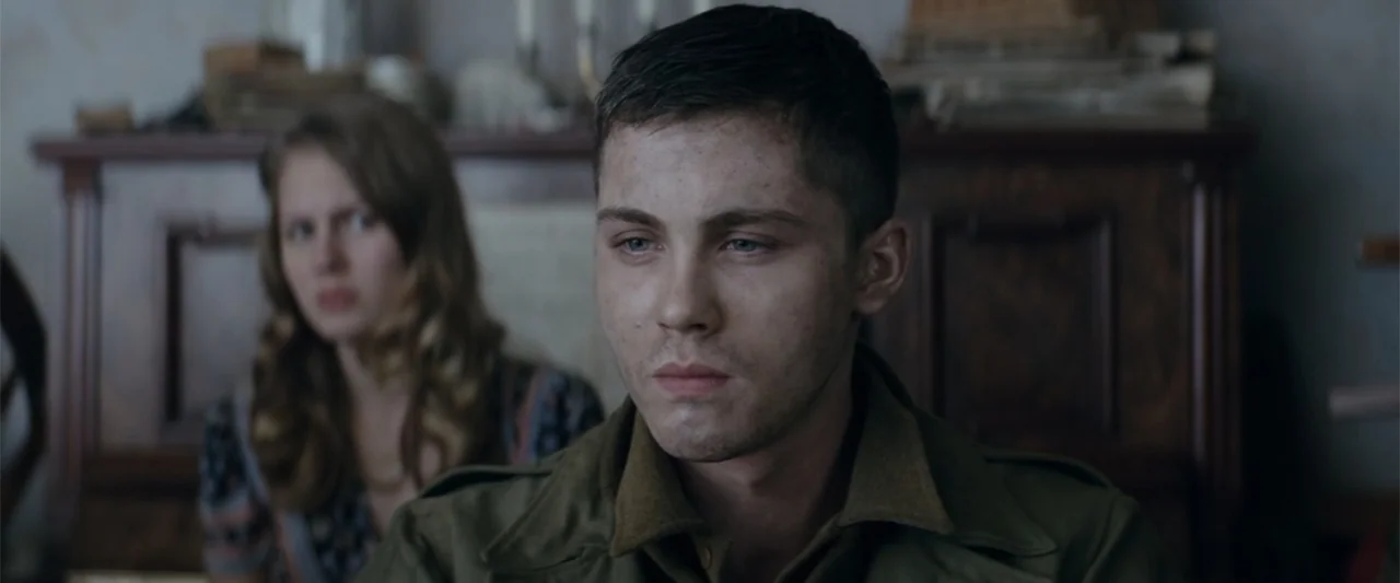 Fury (2014) movie still: medium — A dimly lit interior space features a man in military attire in the foreground. Behind him, a young woman is…