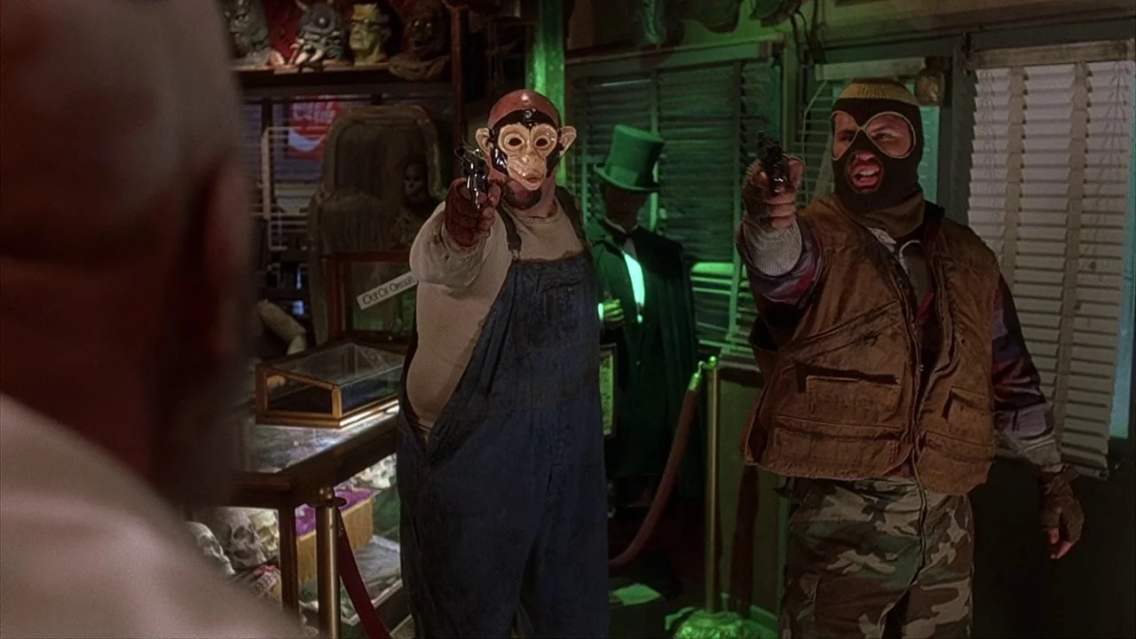 House of 1000 Corpses (2003) movie still: medium — A cluttered shop filled with masks and antiques contains two men holding handguns out. The two…